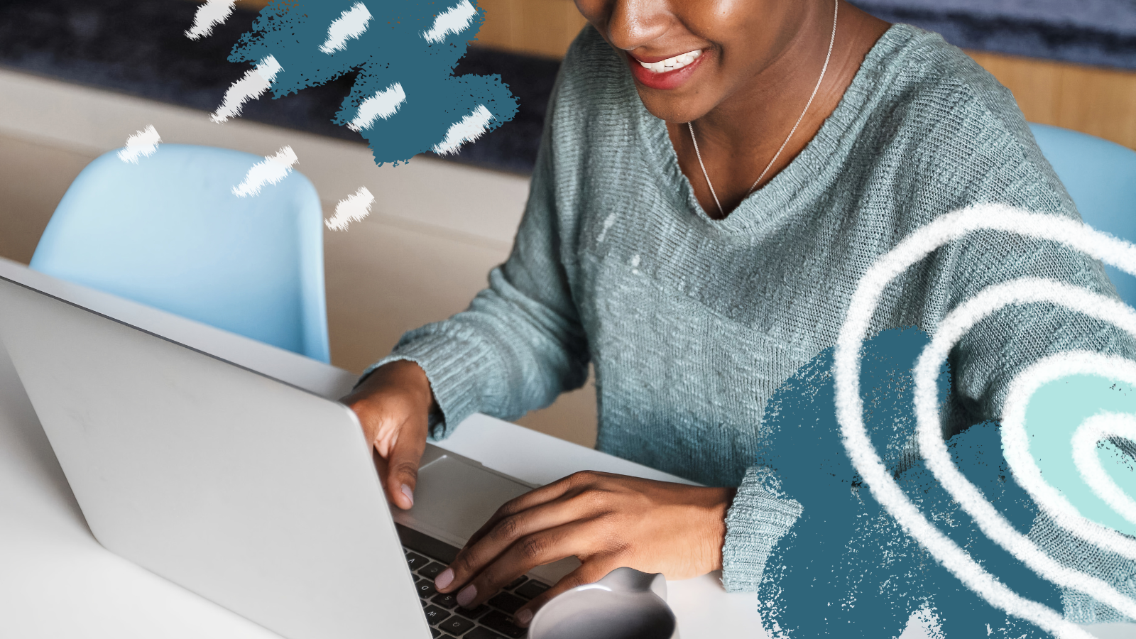 A closeup of a young professional sitting at a desk working on their laptop. They are smiling while looking down at their screen and typing.