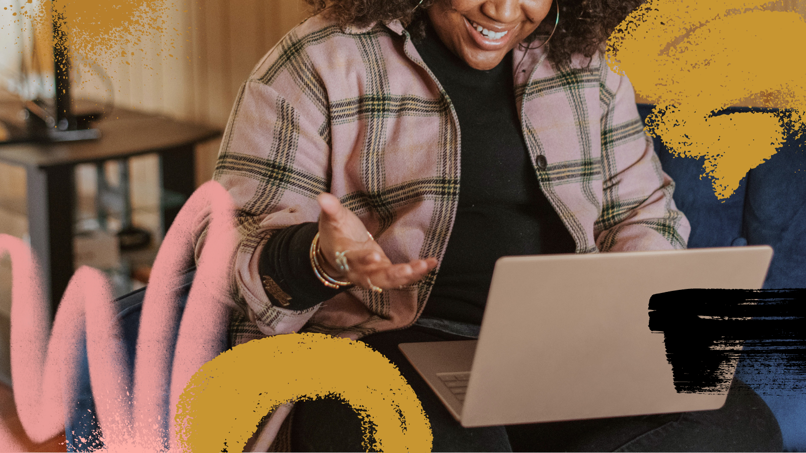 A person sitting on a couch, looking down at their laptop screen having a conversation on a video call. They are using their hands expressively as they speak.
