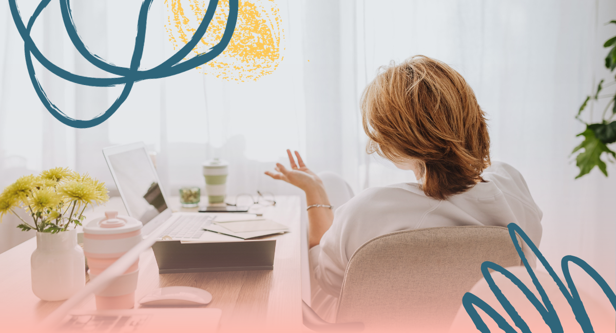 A person is participating in a Zoom meeting from a cozy home setting while seated at a desk.